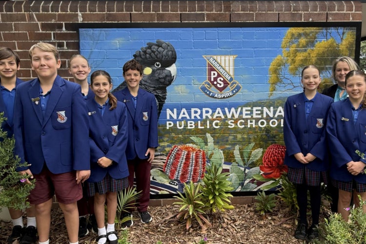 Photo of student leaders wearing blazers in front of school mural