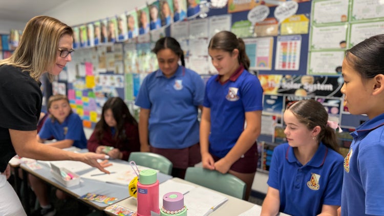 Photo of Year 5 students playing a multifplication game with female teacher