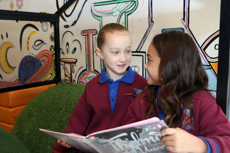 Photo of 2 Year 4 students reading a book in the school library
