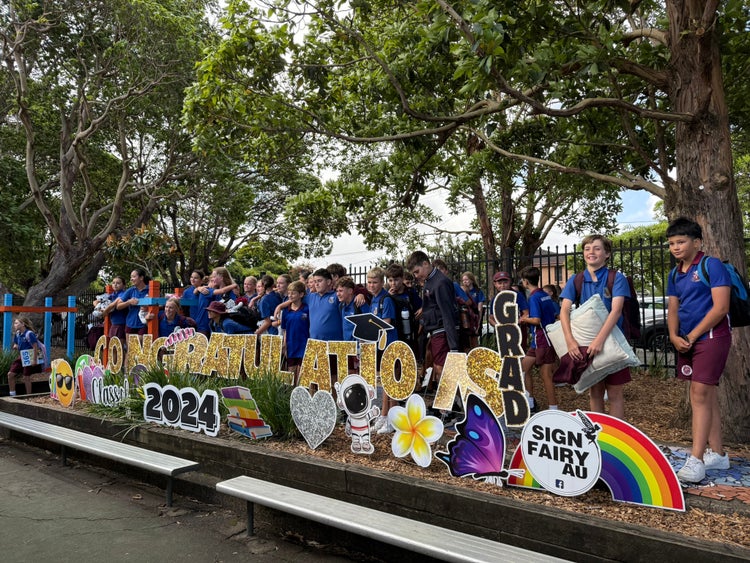 Group of Year 6 students standing behind large graduation sign