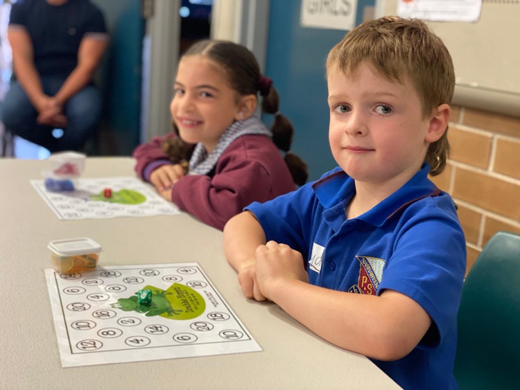 Male and female kindergarten students explaining how to play maths games