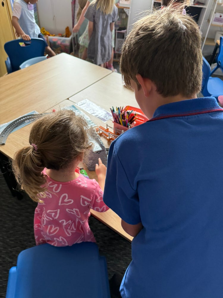 Photo of Year 5 male student helping female pre school student