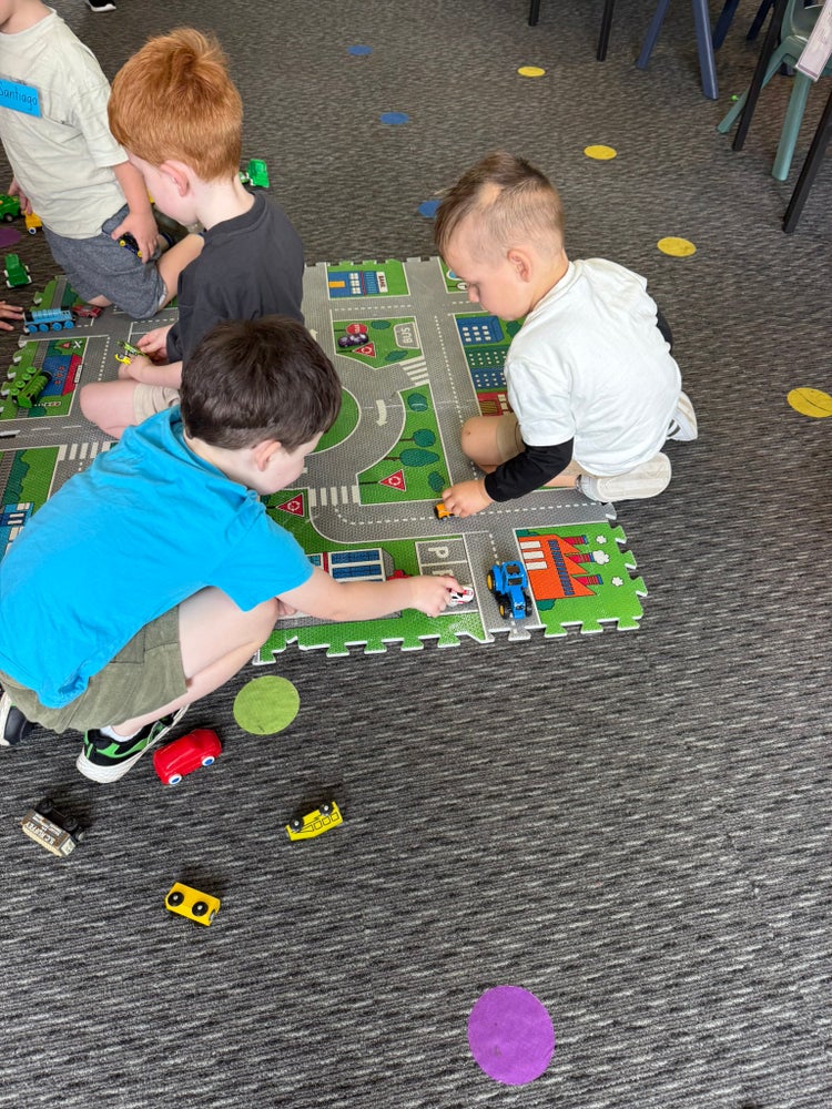 Photo of 3 male preschool students playing with cars