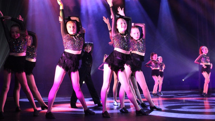 Photo of female and male Year 5 and 6 students on stage dancing wearing black sequin costume