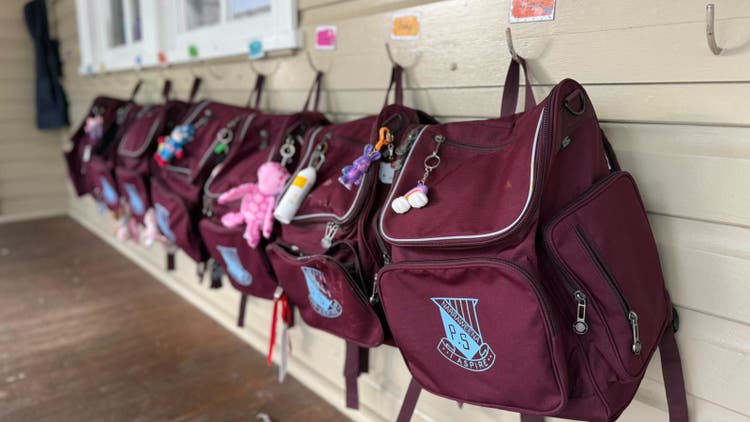 Photo of maroon school bags hanging up outside a classroom