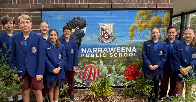 Photo of four male and four female student leaders wearing blue blazers standing in front of school mural with a black cockatoo